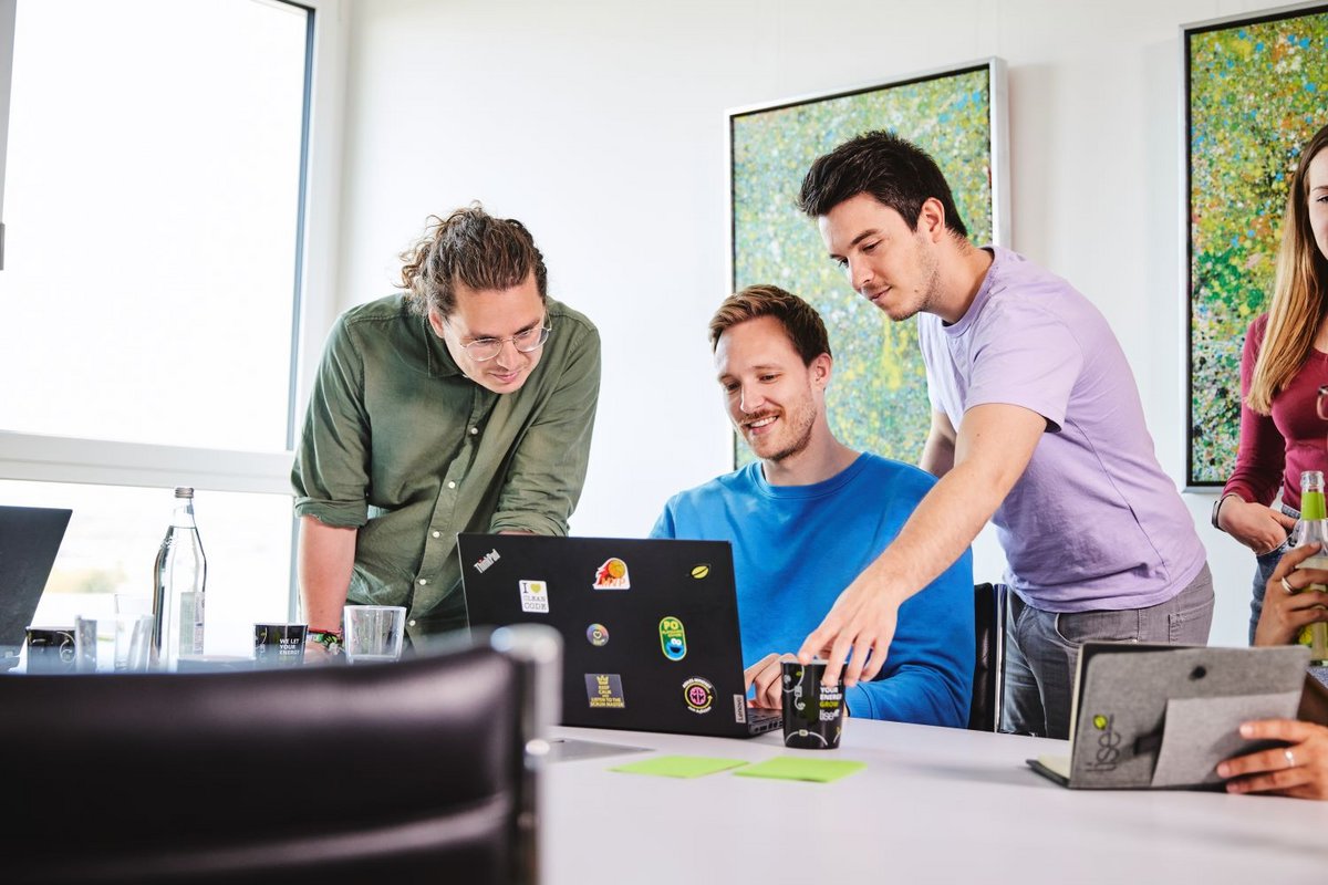 Drei lise-Entwickler arbeiten gemeinsam an einem neuen Projekt mit Hilfe eines Computers und Notizzetteln