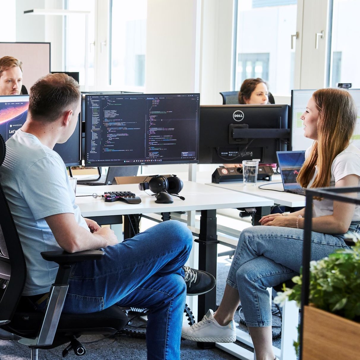 Zwei lise-Entwickler*innen sitzen nebeneinander und bringen mit Hilfe von Programmcodes ein digitales Produkt in die Cloud