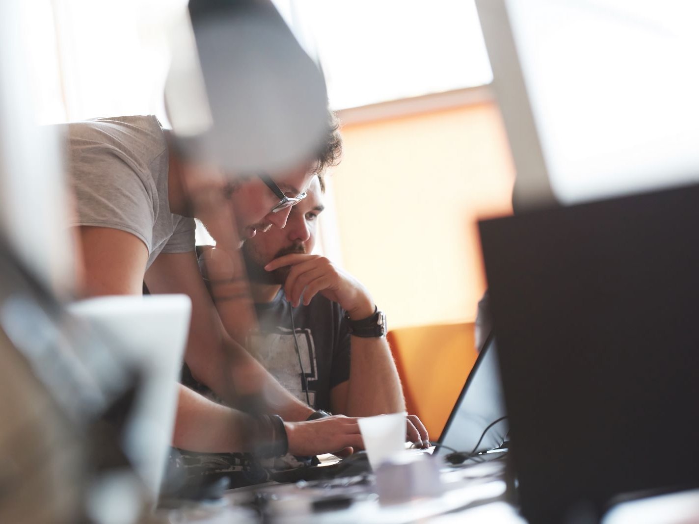 Ein lise-Entwickler zeigt einem anderen etwas auf dem Computer und beide sind sehr konzentriert
