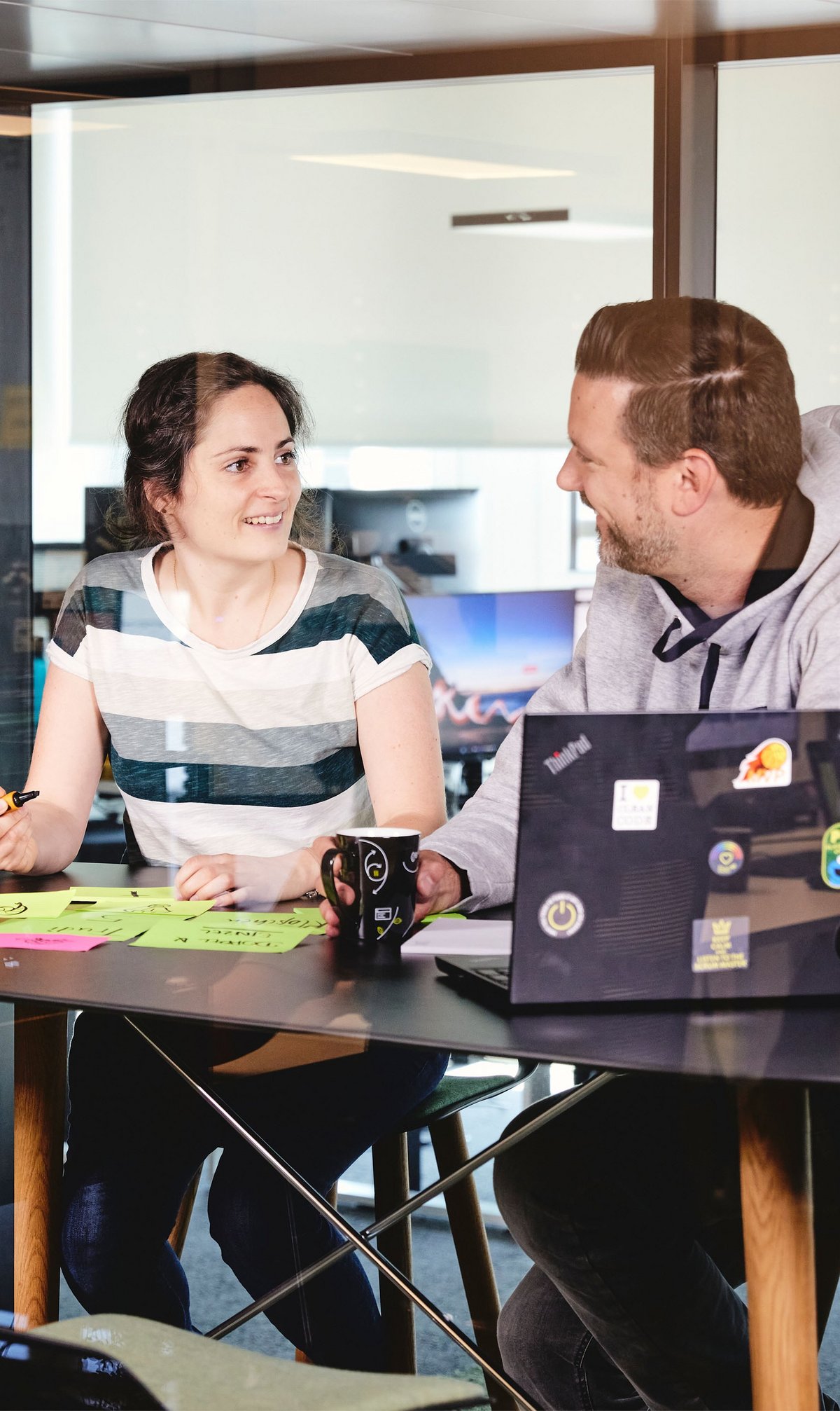 zwei lise-Entwickler*innen, eine mit einem Stift und der andere mit einer Tasse in der Hand, planen gemeinsam das Nutzerfeedback