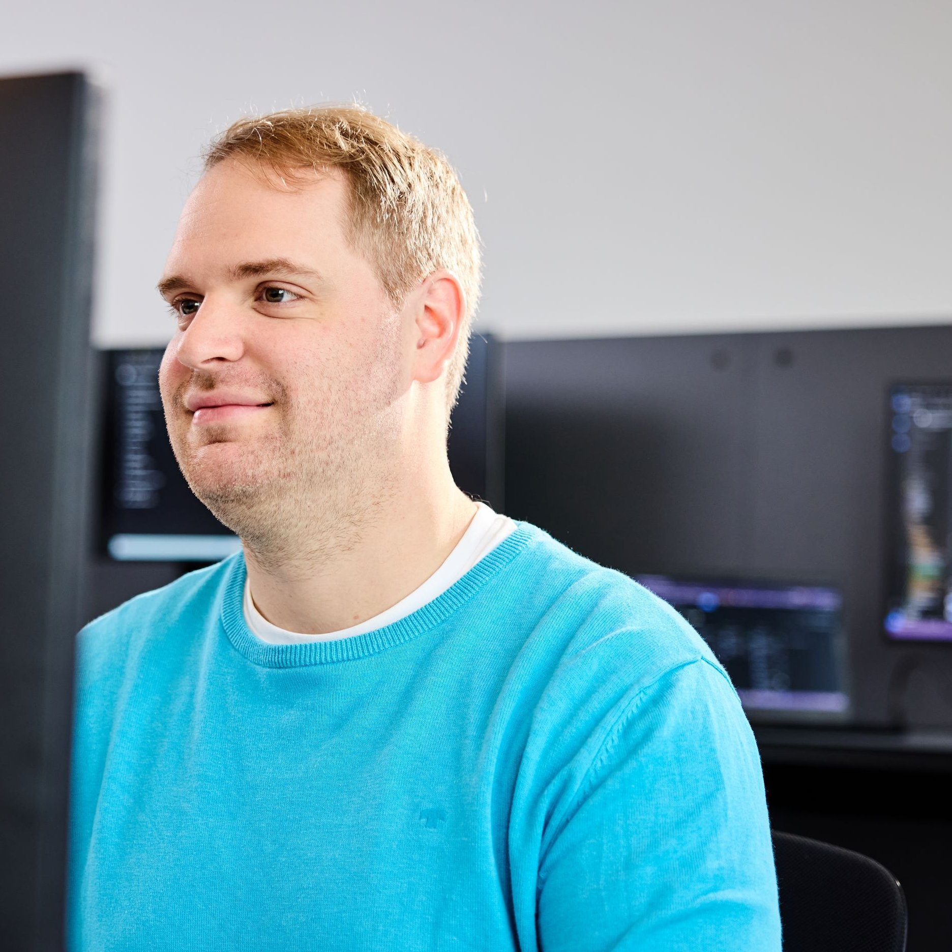 Ein lise-Entwickler mit blauem T-Shirt sitzt am PC um eine Low Code Plattform zu entwickeln