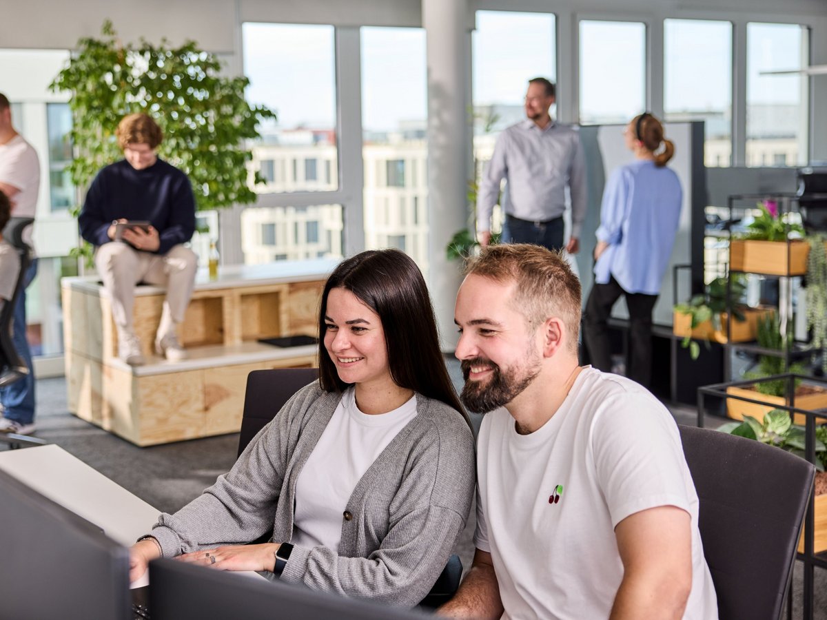 Zwei lise-Entwickler arbeiten gemeinsam an einer neuen Produktentwicklung und im Hintergrund halten sich weitere lise-Mitarbeiter auf