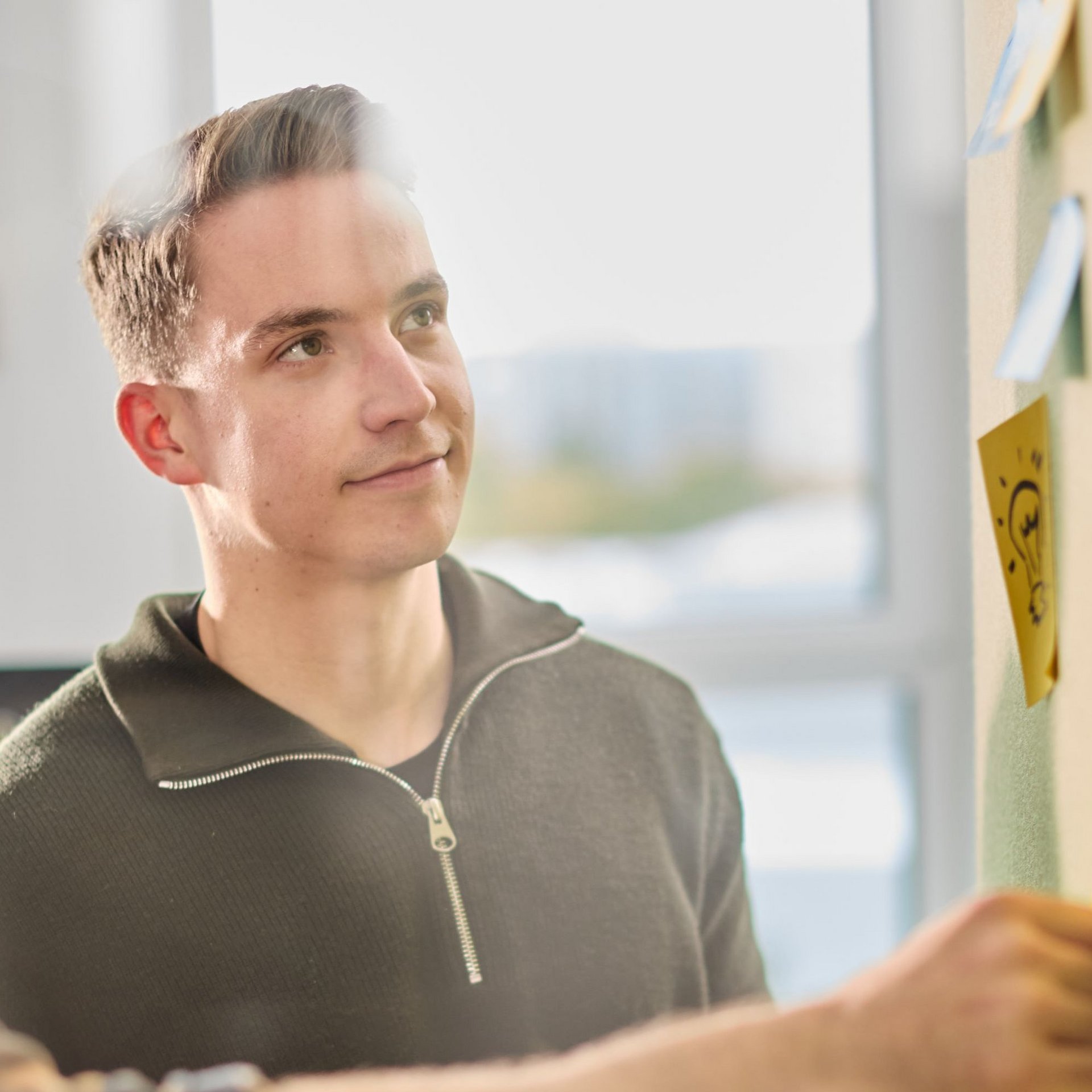 Ein lise-Entwickler betrachtet eine grüne Wand auf der Post Its mit verschiedenen Symbolen zu erkennen sind