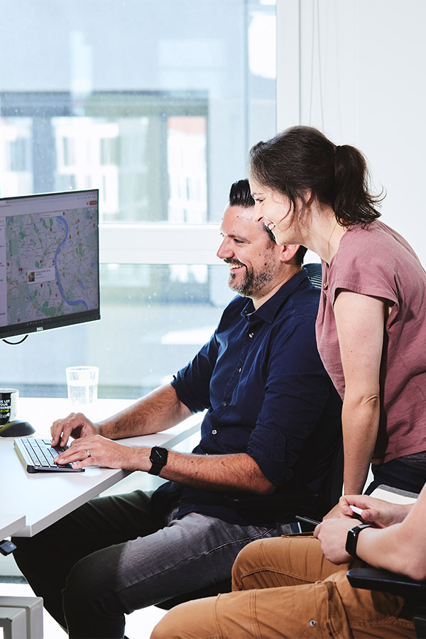 Zwei lise-Entwickler*innen arbeiten zusammen an einem Computer auf dem eine Map mit dem lise-Standort zu sehen ist