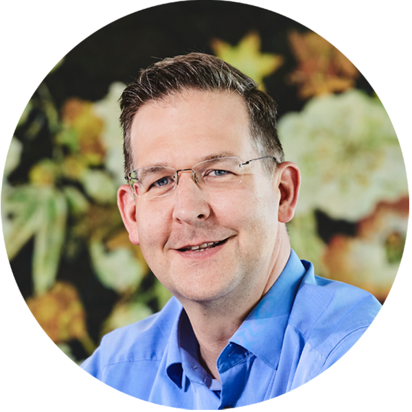 Foto des Geschäftsführers der lise in einem blauen Hemd vor einem bunten Hintergrund