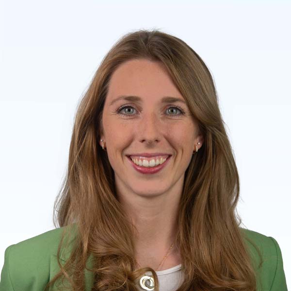 Bild einer dunkelblonden Product Managerin mit einem weißen T-Shirt und einem grünen Jackett